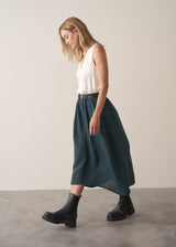 Woman wearing dark green linen cocoon skirt with grey jumper
