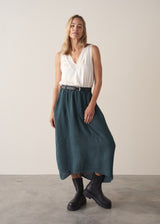 Woman wearing dark green linen cocoon skirt with grey jumper