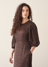 Woman wearing a leopard print dress against a plain background