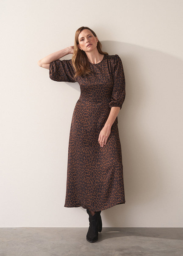 Woman wearing a leopard print satin midi dress against a plain background