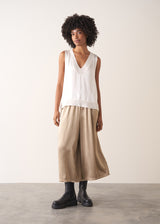 Woman wearing a white sleeveless top against a plain background