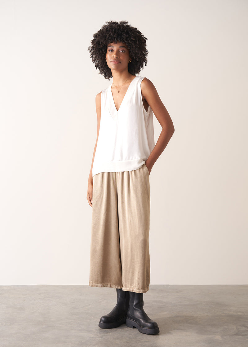 Woman wearing a white sleeveless top against a plain background