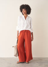 Woman wearing bright red wide leg linen trousers and white v-neck top