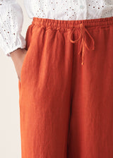 Woman wearing bright red wide leg linen trousers and white v-neck top