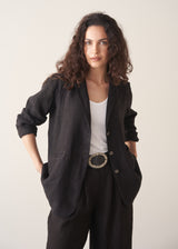 Woman wearing a black linen blazer, black wide leg linen trousers and a white top.