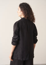 Woman wearing a black linen blazer, black wide leg linen trousers and a white top.