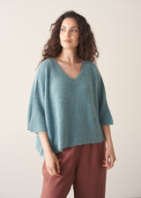 Woman wearing teal knitted sweater and rust red linen trousers
