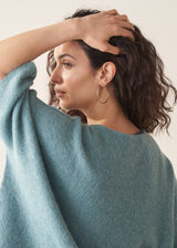 Woman wearing teal knitted sweater and rust red linen trousers