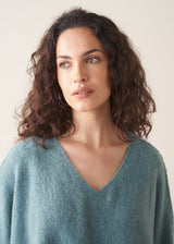 Woman wearing teal knitted sweater and rust red linen trousers