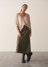 Woman wearing a beige cardigan against a plain background