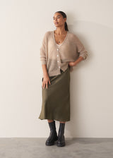 Woman wearing a beige cardigan against a plain background