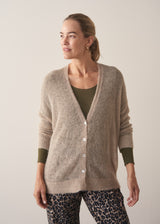 Woman wearing neutral sheer cardigan with. mother of pearl buttons and leopard print barrel leg trousers