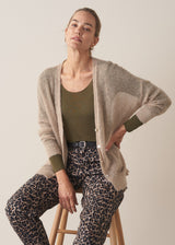 Woman wearing neutral sheer cardigan with. mother of pearl buttons and leopard print barrel leg trousers