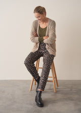 Woman wearing neutral sheer cardigan with. mother of pearl buttons and leopard print barrel leg trousers