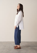 Woman wearing a white boxy shirt and blue jeans 