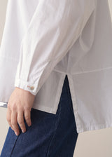 Woman wearing a white boxy shirt and blue jeans 