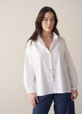 Woman wearing a white boxy shirt and blue jeans 