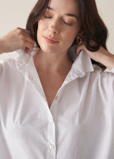 Woman wearing a white boxy shirt and blue jeans 