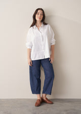 Woman wearing a white boxy shirt and blue jeans 