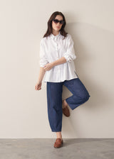 Woman wearing a white boxy shirt and blue jeans 