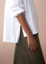 Woman wearing a white boxy cotton shirt with satin skirt
