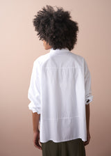 Woman wears a white boxy cotton shirt over a satin skirt