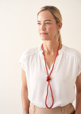 Woman wearing white top and red chunky beaded necklace