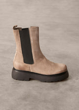 Brown suede Chelsea boot with black sole on a gray background