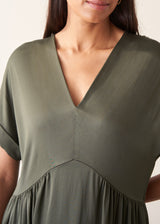 A woman wearing a loose, short-sleeve olive green satin maxi dress with a V-neckline