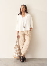 Woman wearing white relaxed boxy shirt and light linen trousers