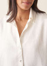 Woman wearing white relaxed boxy shirt and light linen trousers
