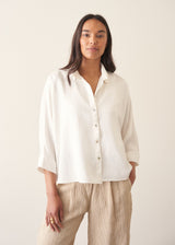 Woman wearing white relaxed boxy shirt and light linen trousers