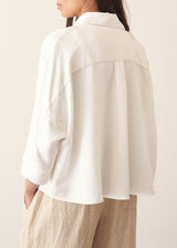 Woman wearing white relaxed boxy shirt and light linen trousers