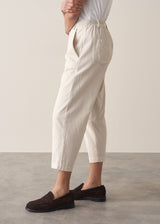 Woman wearing cropped tapered leg cord trousers in oatmeal  with blue linen shirt