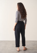 Woman wearing black tapered leg jeans, sandals and a dark stripe sweater