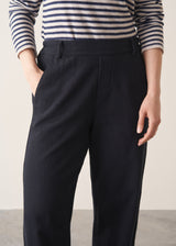 Woman wearing black tapered leg jeans, sandals and a dark stripe sweater