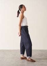 Woman wearing dark blue tapered  denim trousers, a white vest top and leopard print loafers