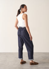 Woman wearing dark blue tapered denim trousers, a white vest top and leopard print loafers