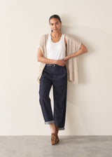 Woman wearing dark blue tapered denim trousers, a white vest top and leopard print loafers