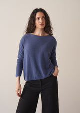 Woman wearing a cornflower blue knit sweater with black wide leg trousers