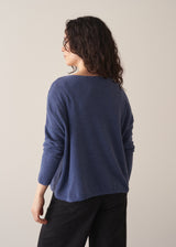Woman wearing a cornflower blue knit sweater with black wide leg trousers