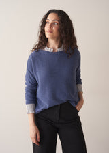 Woman wearing a cornflower blue knit sweater with black wide leg trousers