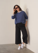 Woman wearing a cornflower blue knit sweater with black wide leg trousers
