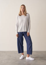 Woman wearing grey relaxed sweater with blue barrel leg jeans
