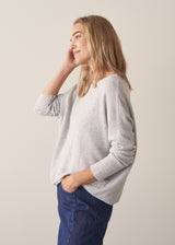 Woman wearing grey relaxed sweater with blue barrel leg jeans