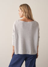 Woman wearing grey relaxed sweater with blue barrel leg jeans