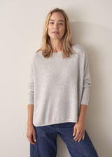 Woman wearing grey relaxed sweater with blue barrel leg jeans
