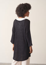 Woman wearing oversized black sweater with off white jeans and black sandals.