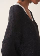 Woman wearing oversized black sweater with off white jeans and black sandals.