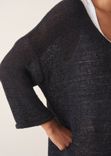 Woman wearing oversized black sweater with off white jeans and black sandals.